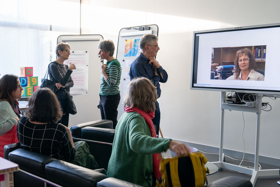Ausstellungsbesucher schauen sich ein Video auf dem Bildschirm an.