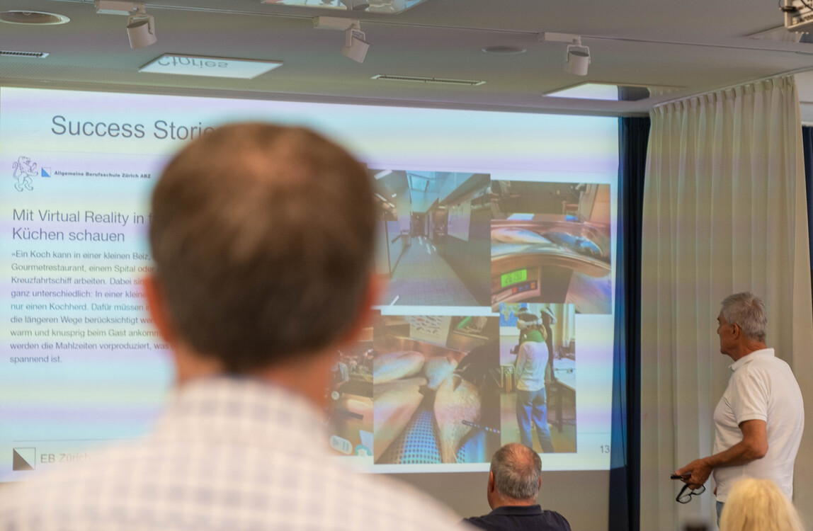 Besucher und Mitarbeiter hören gespannt einer Präsentation zu.