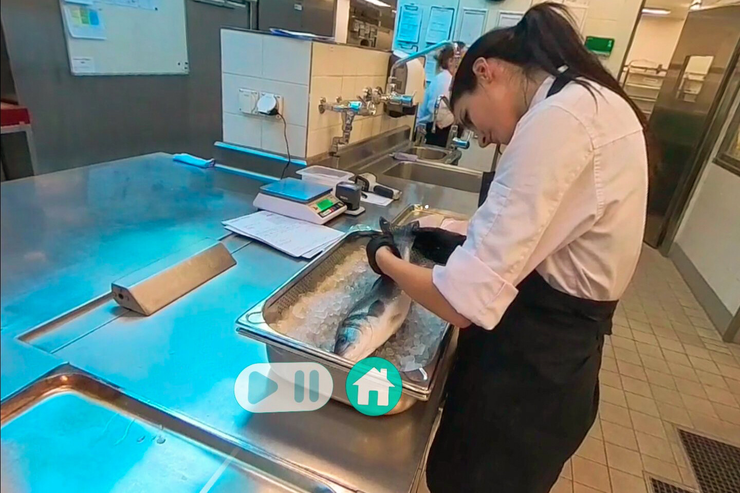 Eine Köchin bereitet in der VR-Ansicht einen Fisch zu.