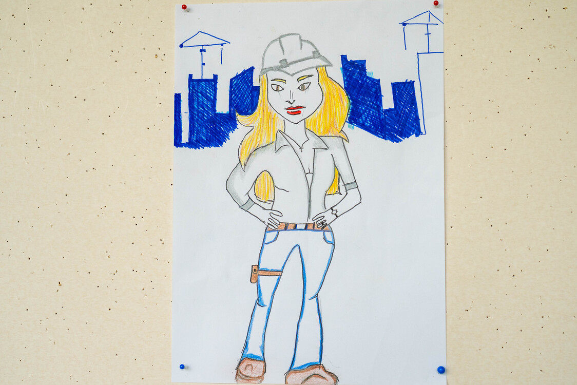 das bild zeigt eine frau mit helm vor einer baustelle mit kränen