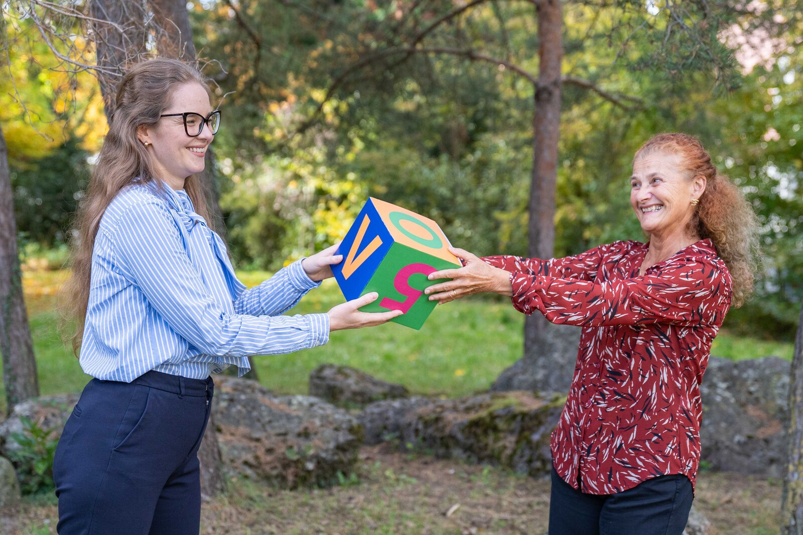 Nora Kindler-Scaltri übergibt Larissa Karkhaneh-Bucher, ihrer Nachfolgerin Grundkompetenzen an der EB Zürich einen Würfel.