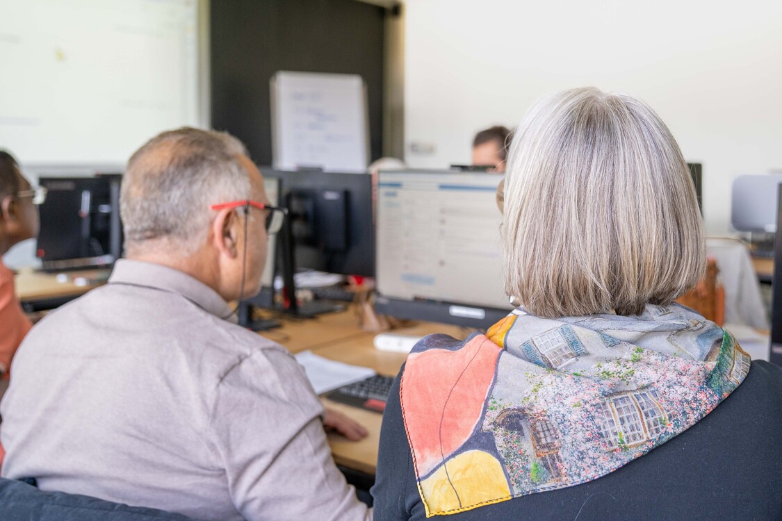 die Kursleiterin unterstützt einen Kursteilnehmer bei einer Übung am Computer