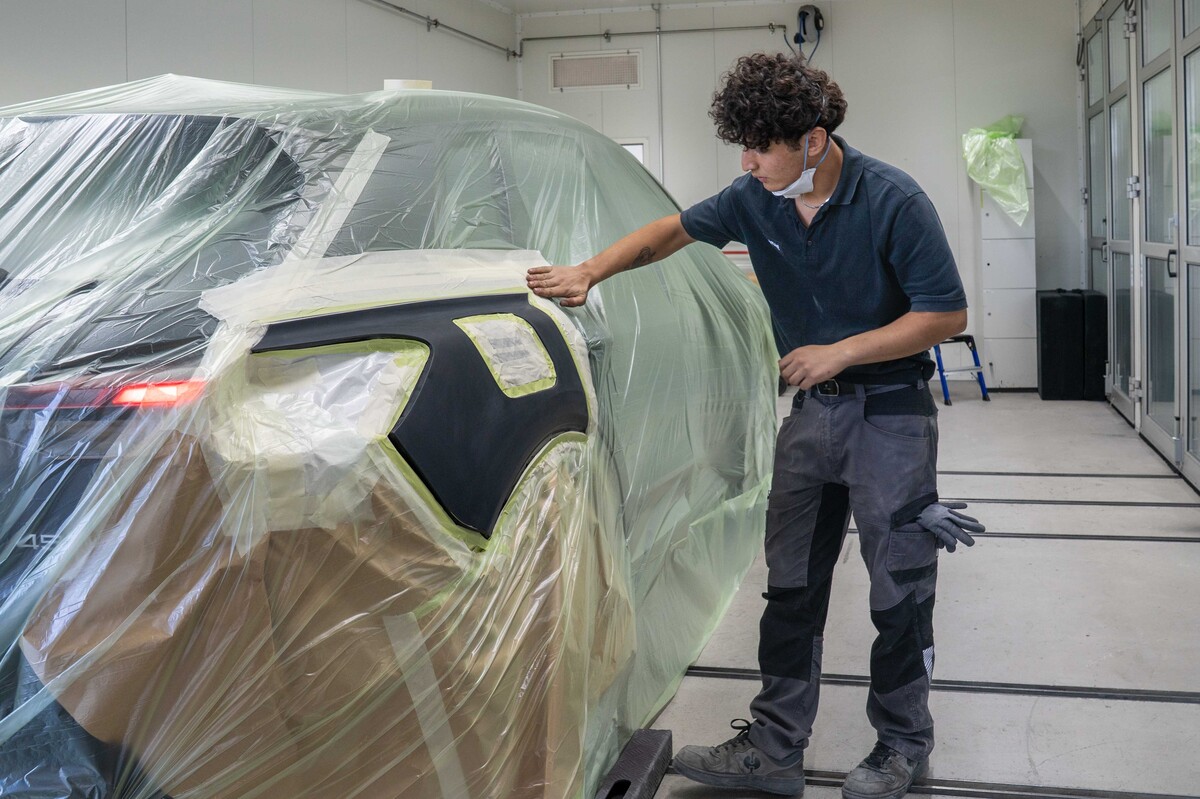 Ein Lernender Carrosserie verpackt bei der AMAG ein Auto und macht es parat fürs Spritzen.
