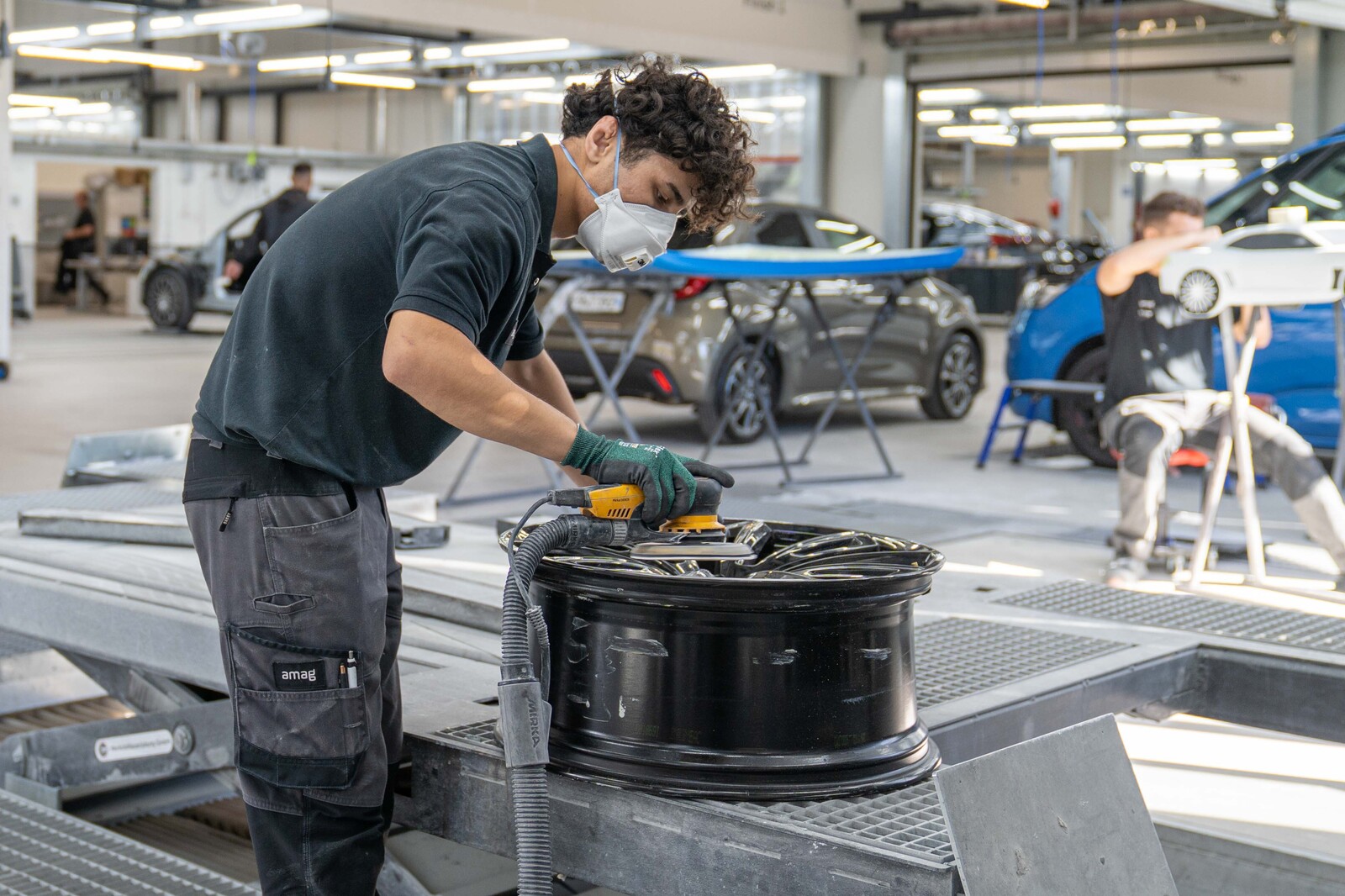 Ein Lernender Carrosserie schleift bei der AMAG eine Autofelge.