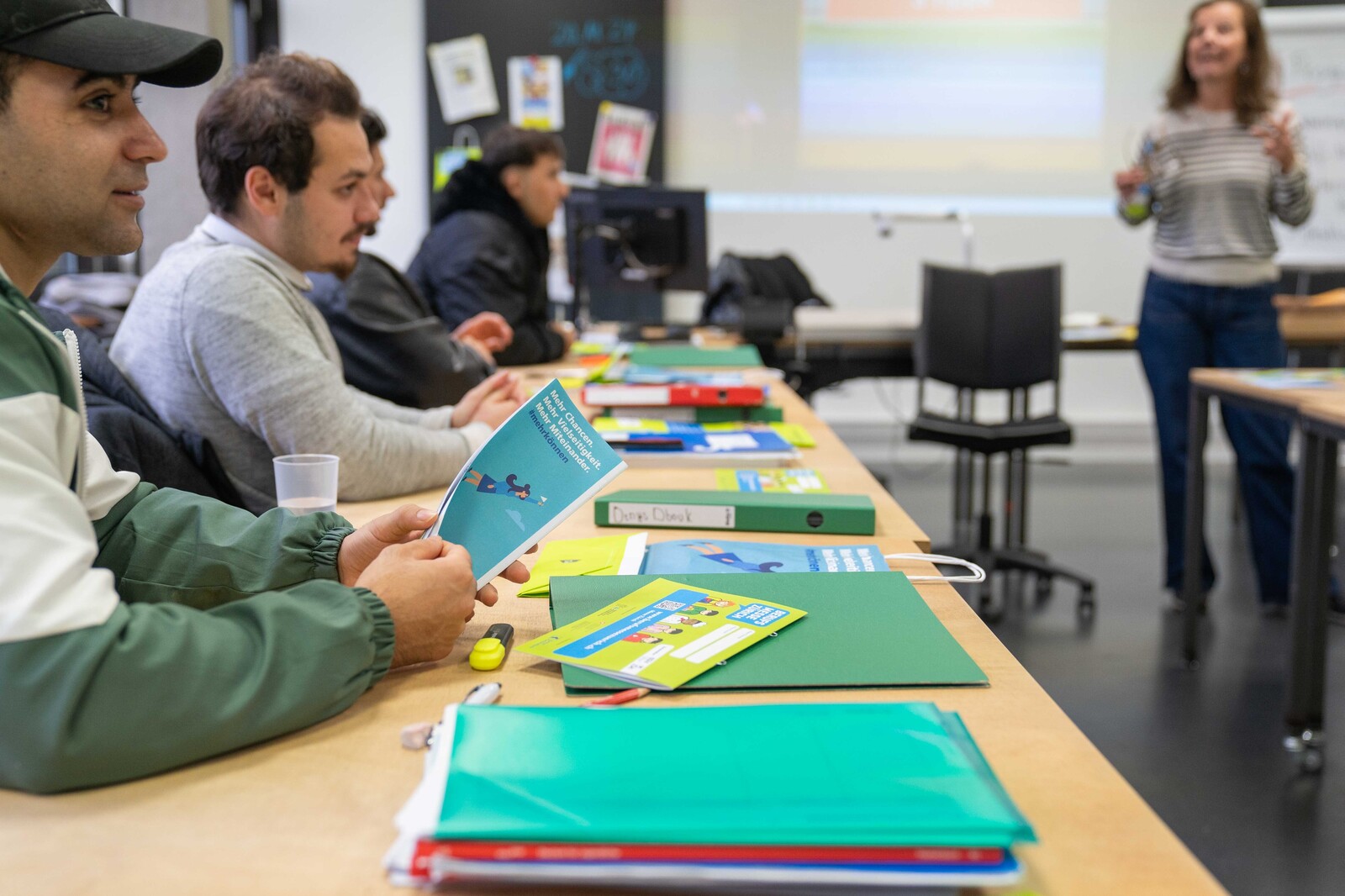 Teilnehmende im Kurse START Berufsbildung hören der Kursleiterin aufmerksam zu.