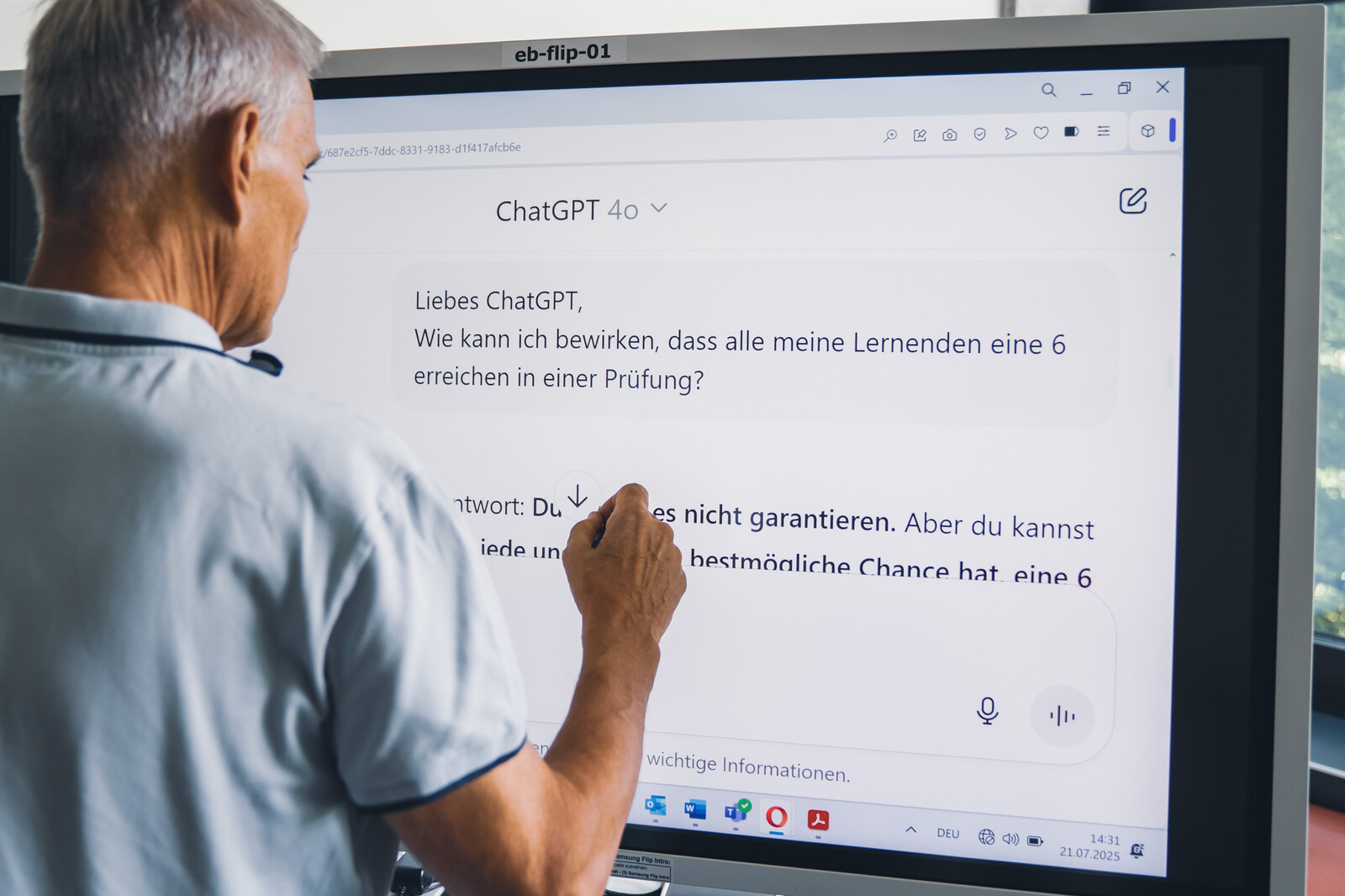 eine Lehrperson steht vor einem grossen Monitor und promptet mit Chat CPT