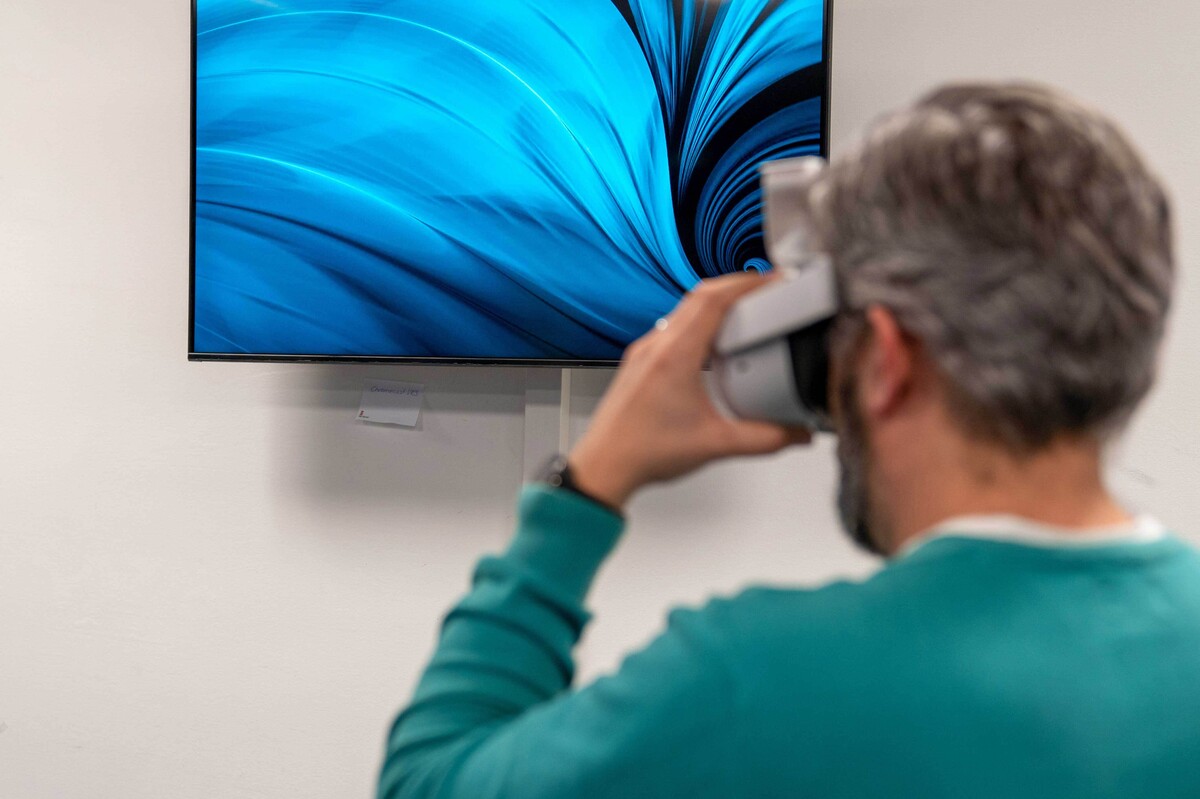 Besuch des VR-Ateliers betrachtet mit VR-Brille einen Monitor.